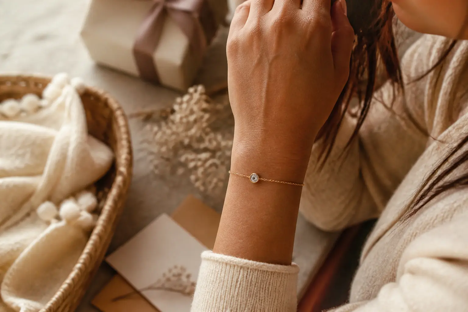 Bracelet pierre naissance délicat au poignet d’une femme, avec breloque gemme, coffret cadeau et carte manuscrite floue