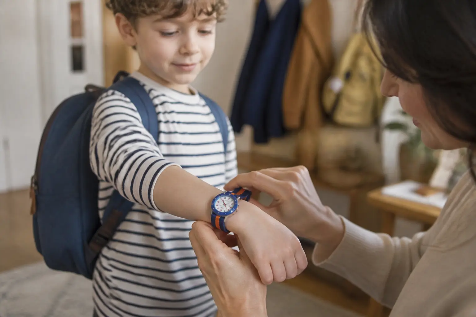 Flik flak montre enfant au poignet d’un enfant de 6 ans, parent ajustant le bracelet, ambiance matin douce et naturelle