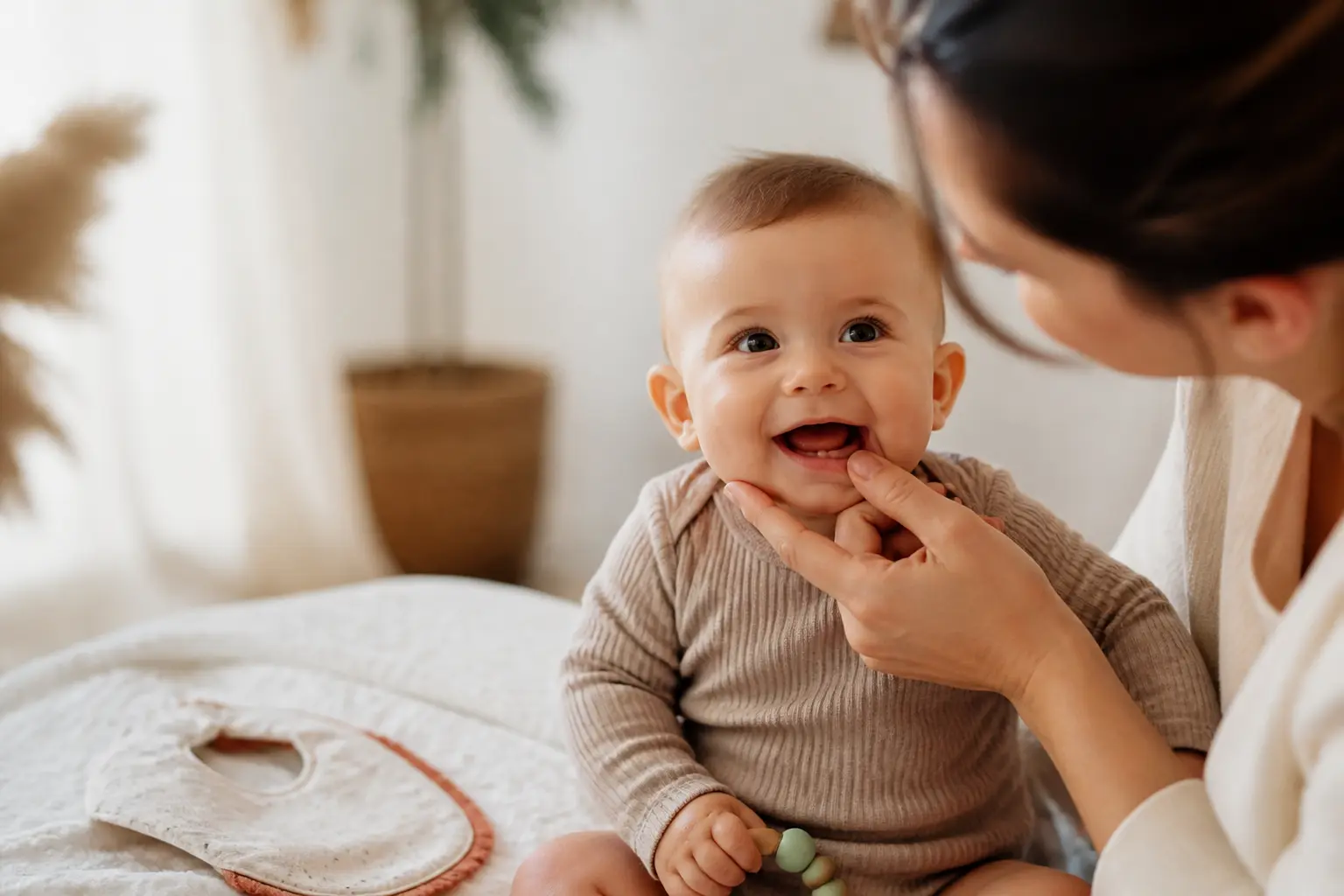 Premiere dent quel age : bébé de 6 mois souriant, parent vérifiant ses gencives, anneau de dentition à côté