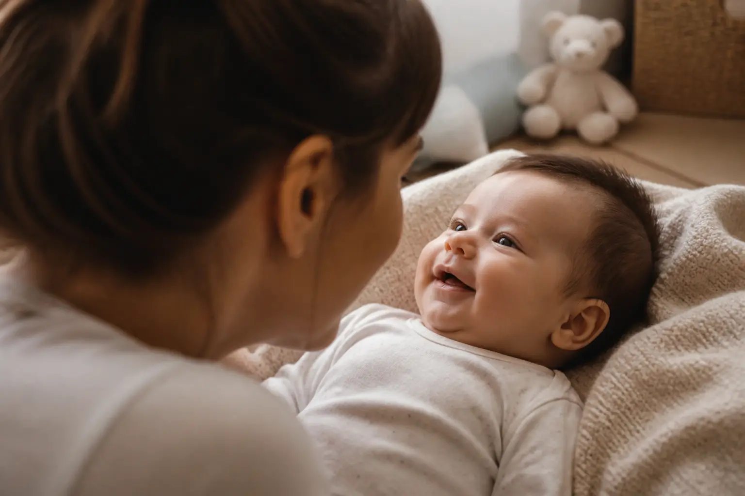 Sourire du bebe lors d’un moment tendre avec un parent, bébé éveillé et regard complice à la maison, lumière douce