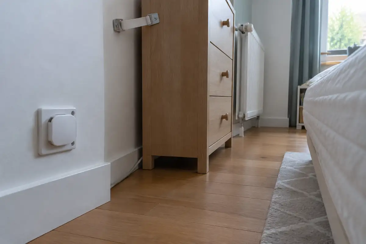 Vue au niveau du sol d'une chambre d'enfant, prise protégée et commode fixée au mur